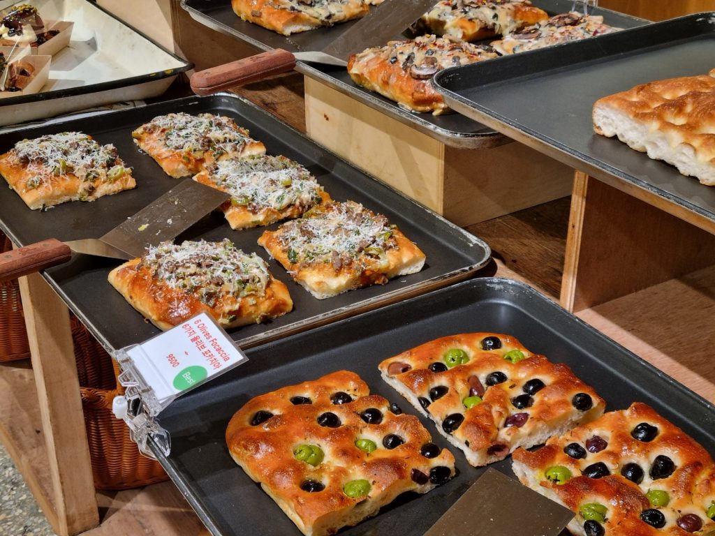 Six-olive focaccia squares with green and black olives on a baking tray at Amor Napoli Anguk