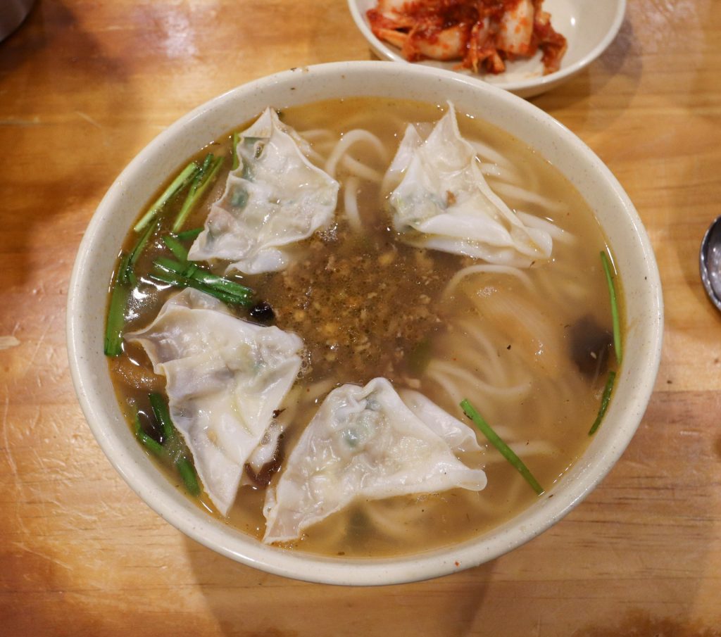 A bowl of kalguksu, knife-cut noodles in broth, with dumplings