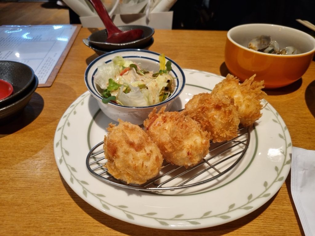 Four crispy shrimp cream croquettes on a wire rack at Kaden Seoul
