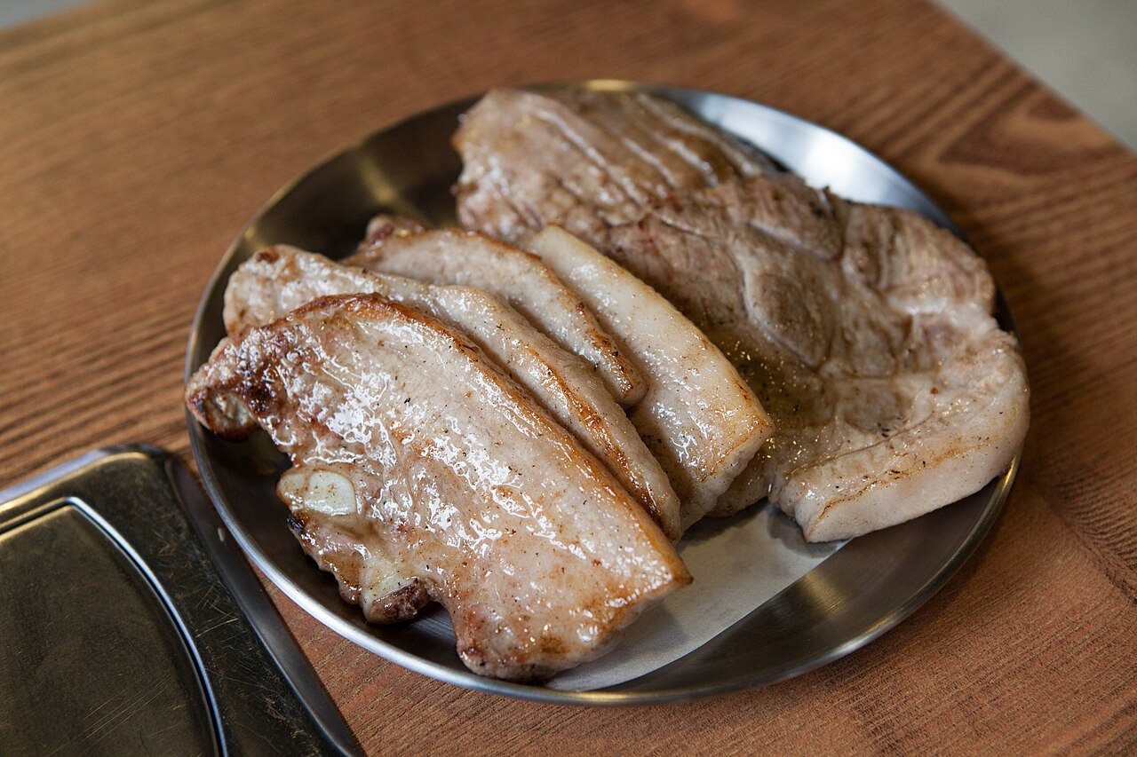 Samgyeopsal pork belly sizzling on a Korean BBQ grill