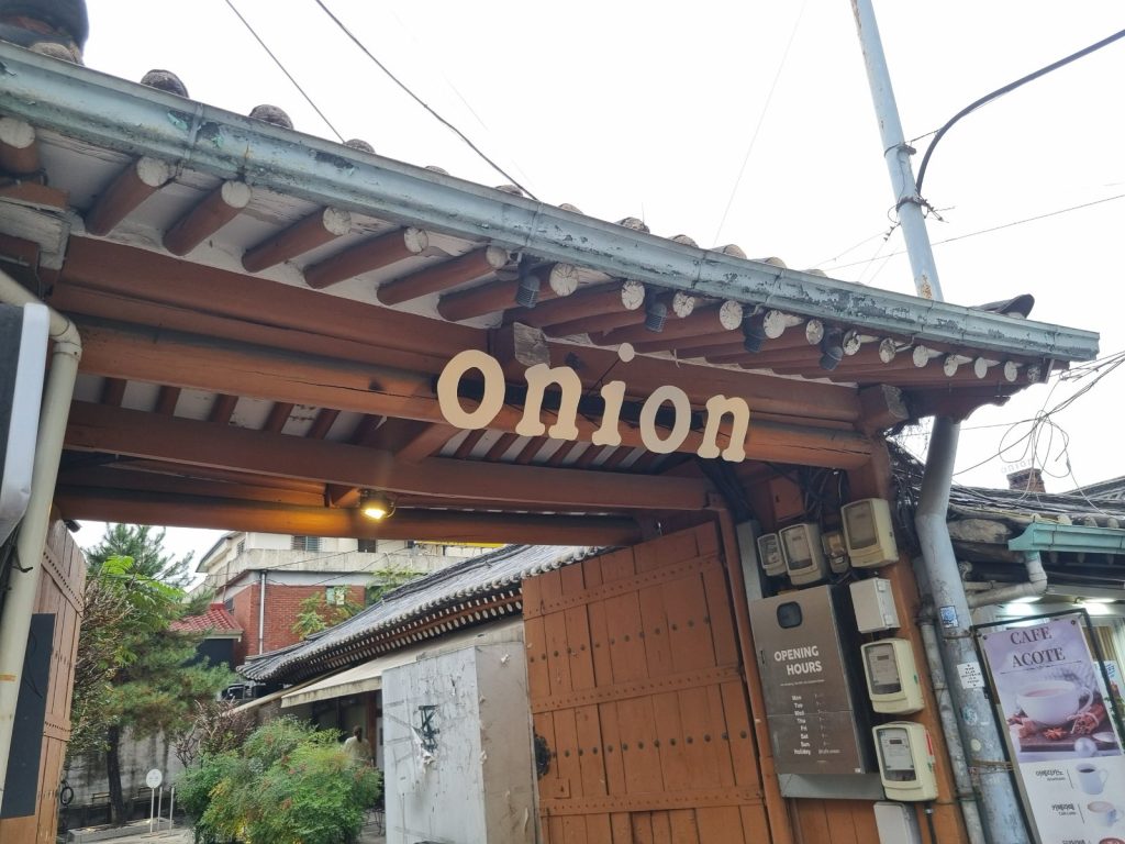 The wooden hanok gate of Onion Anguk café with the onion sign, on a street near Anguk Station