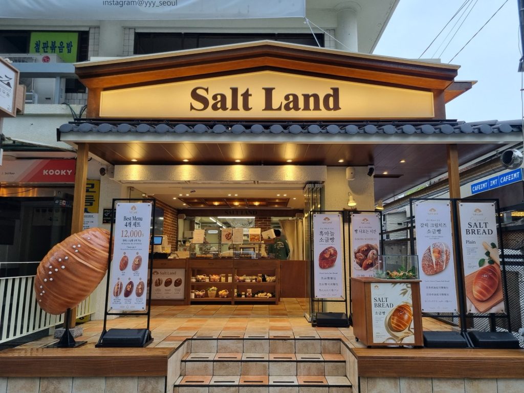 Salt Land salt bread bakery storefront with a giant salt bread sculpture and menu banners near Anguk Station