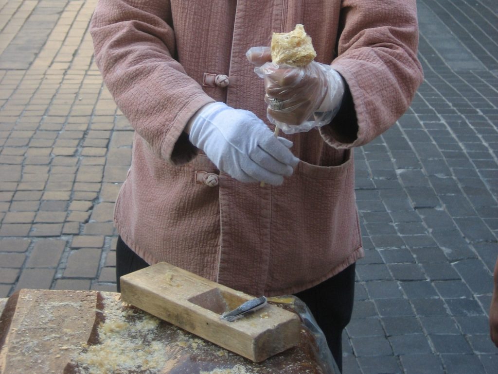 A yeot taffy vendor cutting candy on a Seoul street